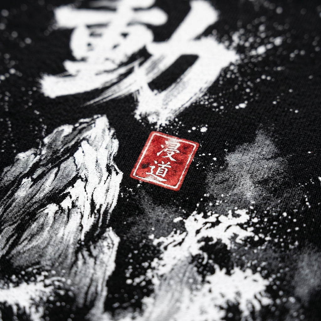 Macro close-up of the Japanese Sumi-e Fudo print on black sweatshirt fabric with red Hanko seal, MINDO Studio