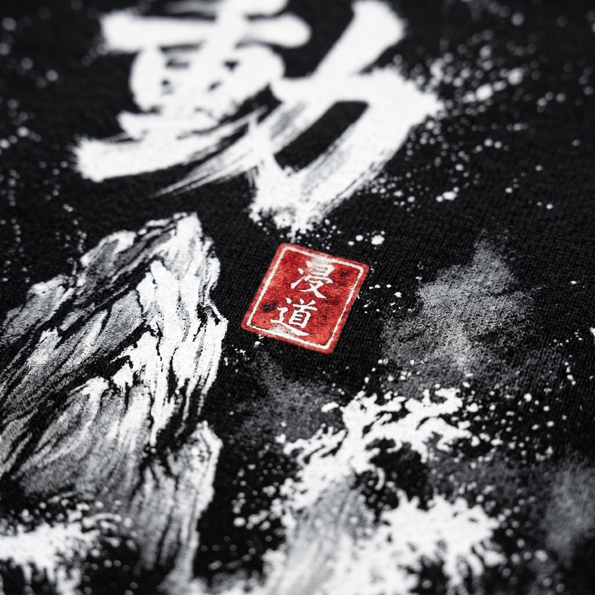 Macro close-up of the Japanese Sumi-e Fudo print on black sweatshirt fabric with red Hanko seal, MINDO Studio