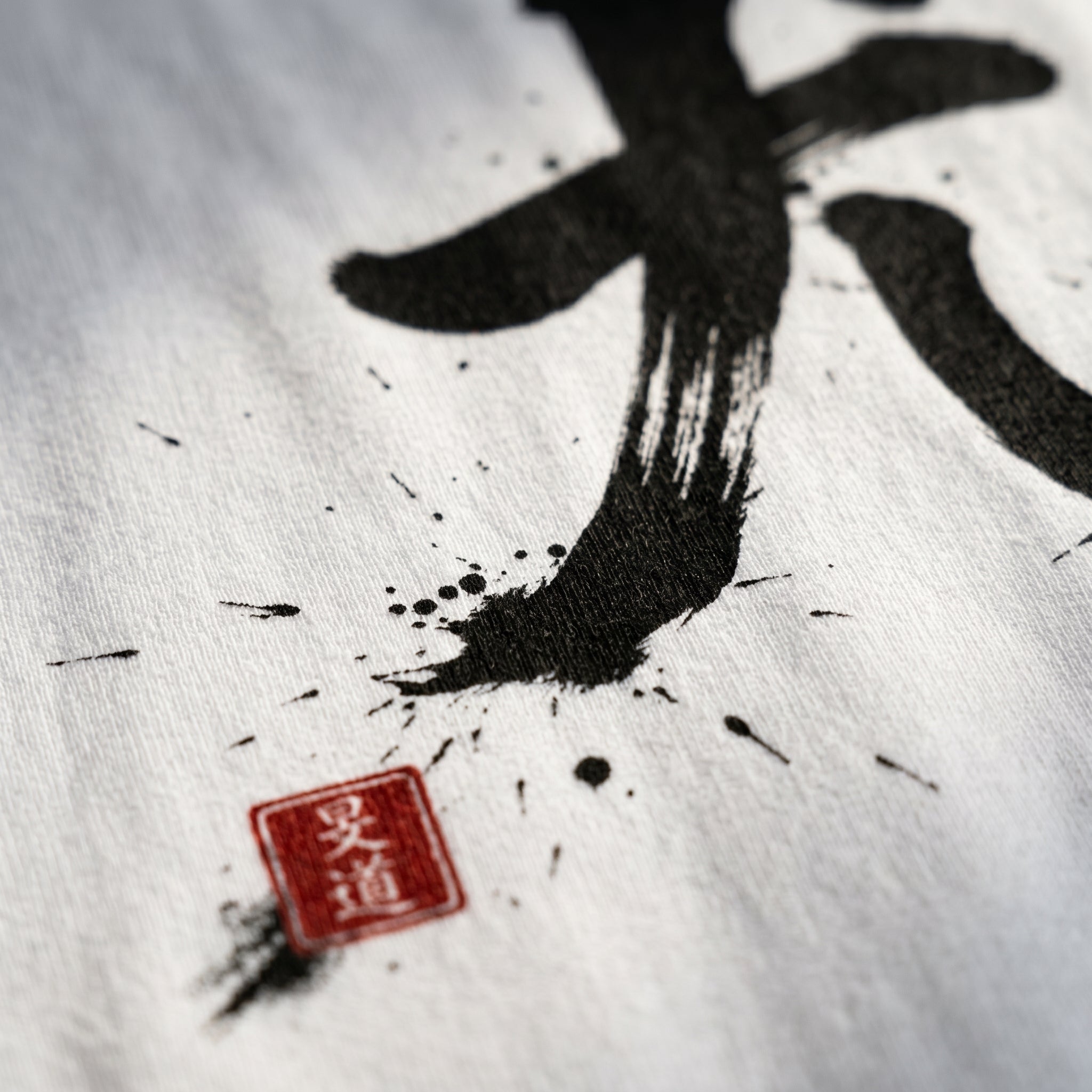 White boxy t-shirt by Mindō Studio featuring black ink Dairiki martial Japanese calligraphy and a red hanko seal